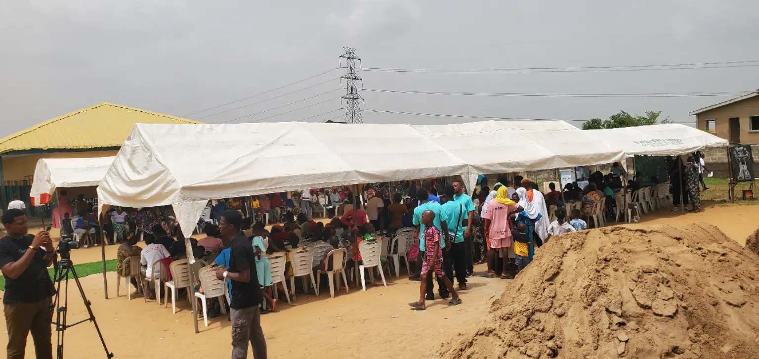 Community members at an outreach event under canopies